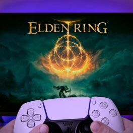 Monitor care are jocul Elden Ring pe ecran, cu un utilizator care ține un controller în mână în fața lui. Elden Ring a primit unele dintre cele mai bune recenzii din istorie