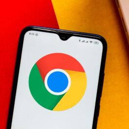 Logoul Google Chrome, înainte să fie schimbat, pe ecranul unui telefon mobil, lângă o tastatură