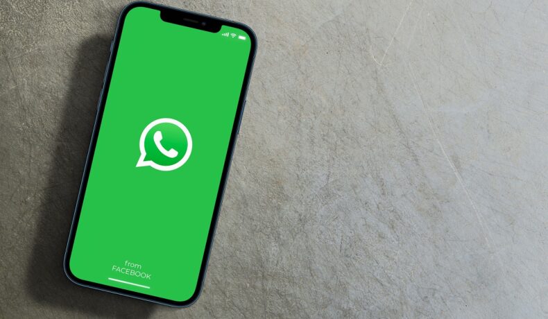 Telefon cu WhatsApp pe ecran, pe un fundal gri. Există unele greșeli prin care poți pierde accesul la contul WhatsApp