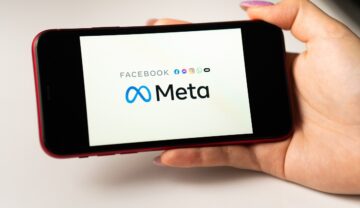 Telefon ținut în mână de un utilizator, cu simbolul Meta pe ecran, pe un fundal alb. Meta va introduce avataruri 3D și pentru Instagram Stories