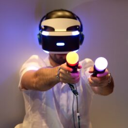 Utilizator care are casca PlayStation VR pe cap și baghetele PSVR în mână, pe fundal alb. Sony a dezvăluit acum designul PlayStation VR2