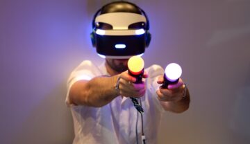 Utilizator care are casca PlayStation VR pe cap și baghetele PSVR în mână, pe fundal alb. Sony a dezvăluit acum designul PlayStation VR2