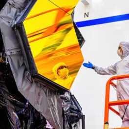 Un cercetător care se uită în oglinda galbenă a Telescopului James Webb, ce ar putea detecta viața extraterestră