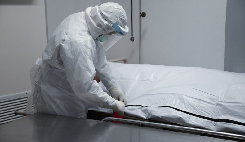 Medic legist care deschide sacul în care se află un corp, la morgă, similar cu un bărbat declarat decedat de 3 doctori