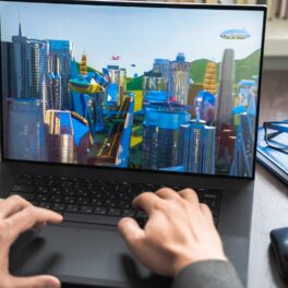 Utilizator care se joacă un joc cu clădiri SF pe un laptop. Vânzările proprietăților din metavers au crescut semnificativ