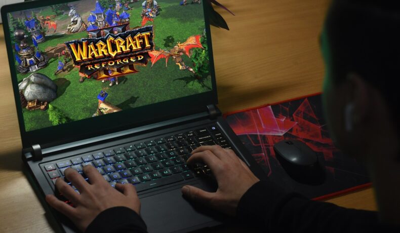 Jucător care e la calculator și se joacă Warcraft, precursrul World of Warcraft, ce va permite acum jucătorilor să joace împreună