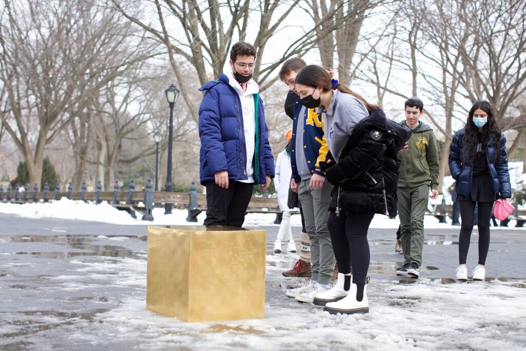 Cetățeni din New York care se uită la Castello Cube, Central Park, februarie 2022. Cubul de aur stă pe zăpadă