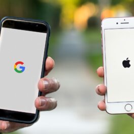 Doi utilizatori care țin telefoane în mână, unul un iPhone cu Apple pe ecran, celălalt Android, cu Google pe ecran. Apple și Google opresc vânzarea produselor în Rusia