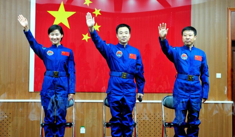 Liu Yang și colegii săi din misiunea Shenzhou IX, 2012, toți 3 ămbrăcați în costum albastru, cu steagul Chinei roșu pe fundal. China va deschide stația spațială Tiangong pentru turiști