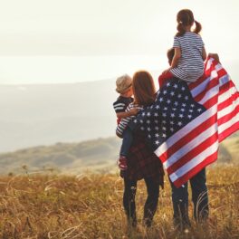 Familie cu 2 părinți și 2 copii, cu steagul american, care stau pe un deal și se uită la apus. Expunerea la plumb ar fi redus IQ-ul populației SUA