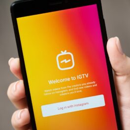 Utilizator care are un telefon în mână, cu aplicația IGTV portocalie pe ecran. Instagram a anunțat că va închide aplicația IGTV