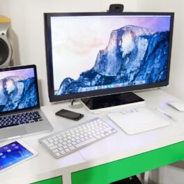 Birou alb cu verde pe care se află un monitor Apple, un Mac mini, tastaură Apple și alte dispozitive. Apple a dezvăluit noile modele de iPad și Mac
