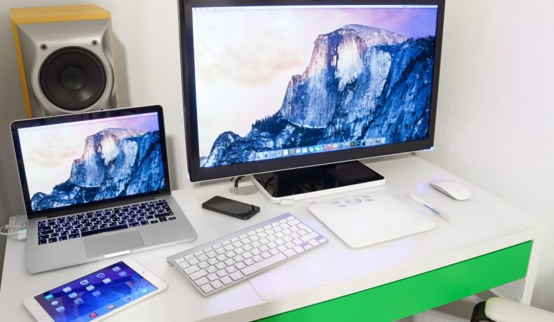 Birou alb cu verde pe care se află un monitor Apple, un Mac mini, tastaură Apple și alte dispozitive. Apple a dezvăluit noile modele de iPad și Mac