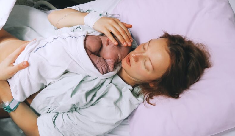 Femeie aflată în patul de spital, care își ține în brațe copilul nou=născut. O femeie din SUA a fost considerată decedată pentru 45 de minute după ce a născut