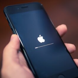 Telefon iPhone, ținut în mână de un utilizator, în timp ce se actualizează. Apple avertizează toți utilizatorii iPhone să instaleze actualizarea 15.4.1
