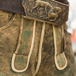 Pereche de pantaloni tradițională din Austria, din piele, cu o curea de bronz cu cerbi. Are o culoare similară cu cea mai veche pereche de pantaloni din lume