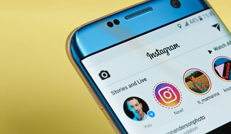 Telefon pe fundal galben, cu aplicația Instagram deschisă. Experții au dezvăluit cum poi urmări anonim imaginile Instagram Stories