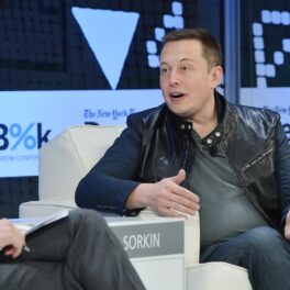 Elon Musk, în cadrul conferinței New York Times 2013 DealBook, New York, 2013. Stă pe un fotoliu alb, cu un fundal albastru. Elon Musk a dezvăluit recent de ce nu vrea să trăiască mai mult
