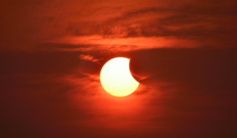 Eclipsă parțială de Soare, precum eclipsa solară de pe 30 aprilie 2022, pe fundal roșu