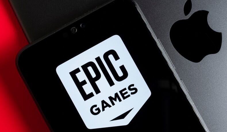 Telefon mobil pe care apare logoul Epic Games, pe fundal de laptop de Mac. Epic Games a dezvăluit recent Unreal Engine 5