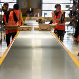 Angajați Amazon care cară pachete, pe o bandă metalică. Primul sindicat al muncitorilor Amazon a fost format în Staten Island