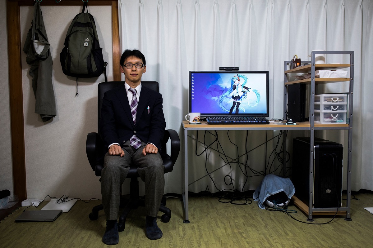 Akihiko Kondo, care sta la birou, cu un ecran cu Hatsune Miku