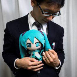 Akihiko Kondo, un bărbat „fictosexual” care s-a căsătorit cu o hologramă, care ține în brațe păpușă cu Hatsune Miku