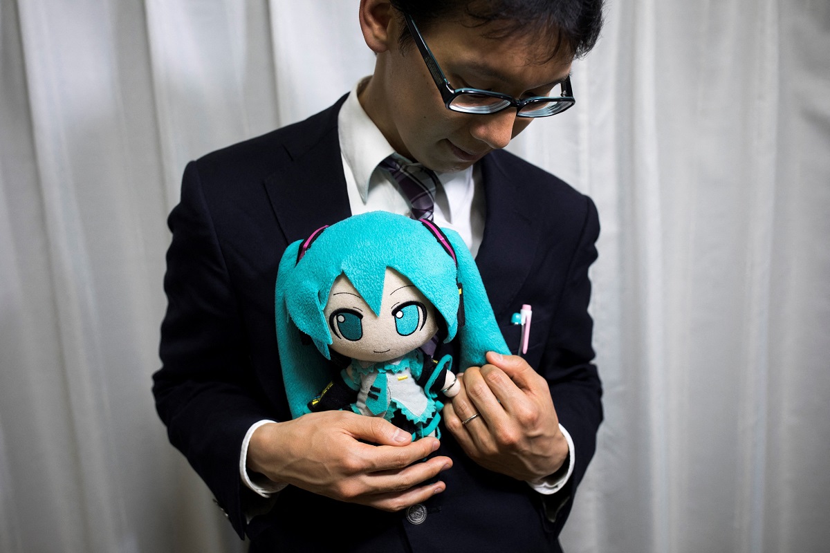 Akihiko Kondo, un bărbat „fictosexual” care s-a căsătorit cu o hologramă, care ține în brațe păpușă cu Hatsune Miku