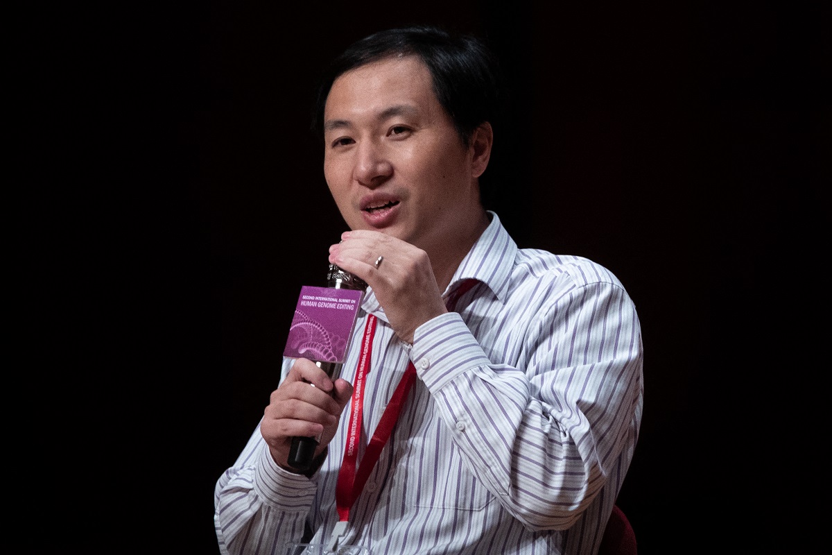 He Jiankui, conferința Second International Summit on Human Genome Editing, 2018, Hong Kong, cu un telefon în mână, fundal negru
