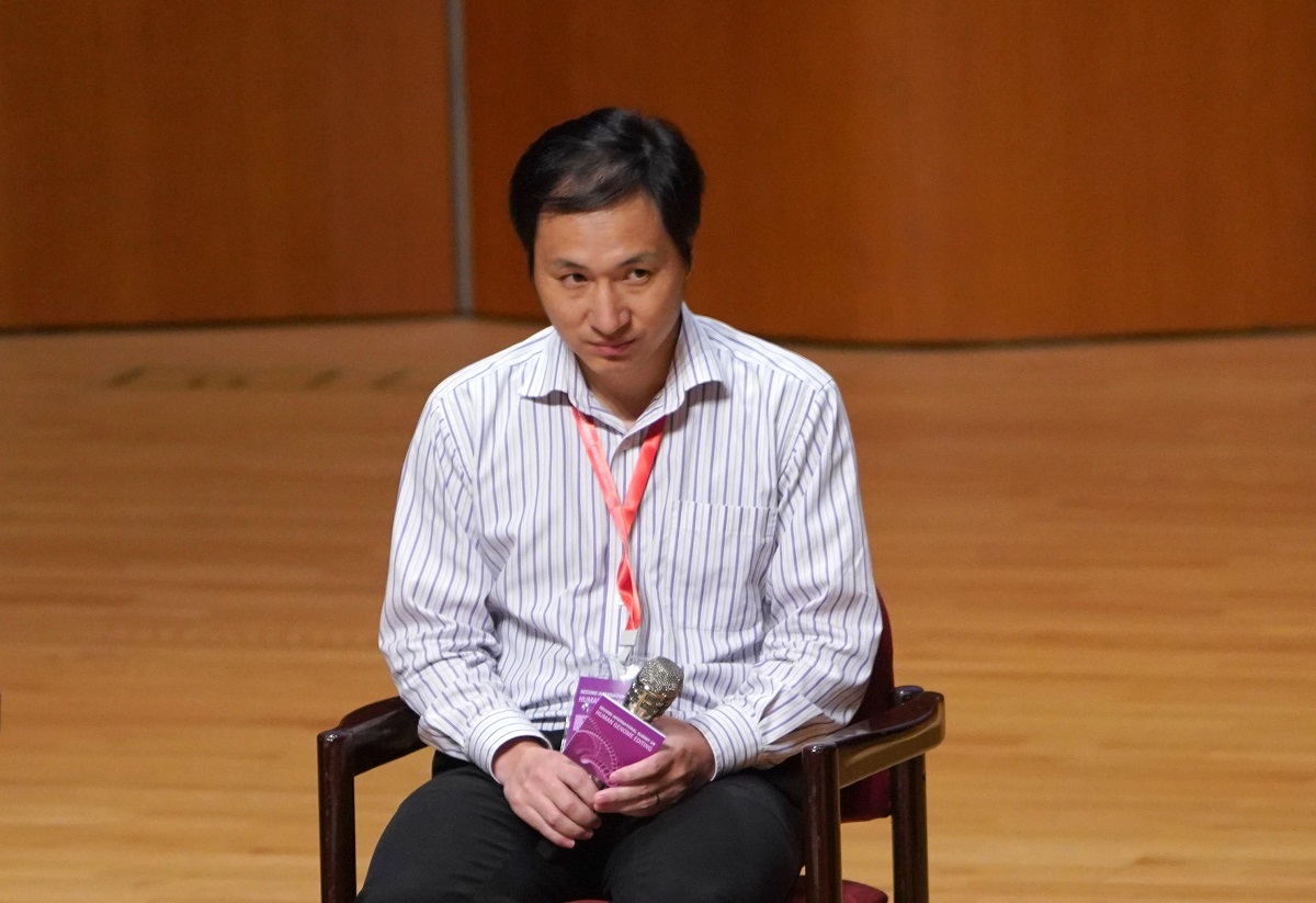 He Jiankui, la Second International Summit on Human Genome Editing, 2018, stând pe un scaun pe scenă