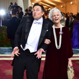 Elon Musk și Maye Musk pe covorul roșu MET Gala 2022. El poartă un costum negru, cămașă albă, și ea poartă o rochie roșie