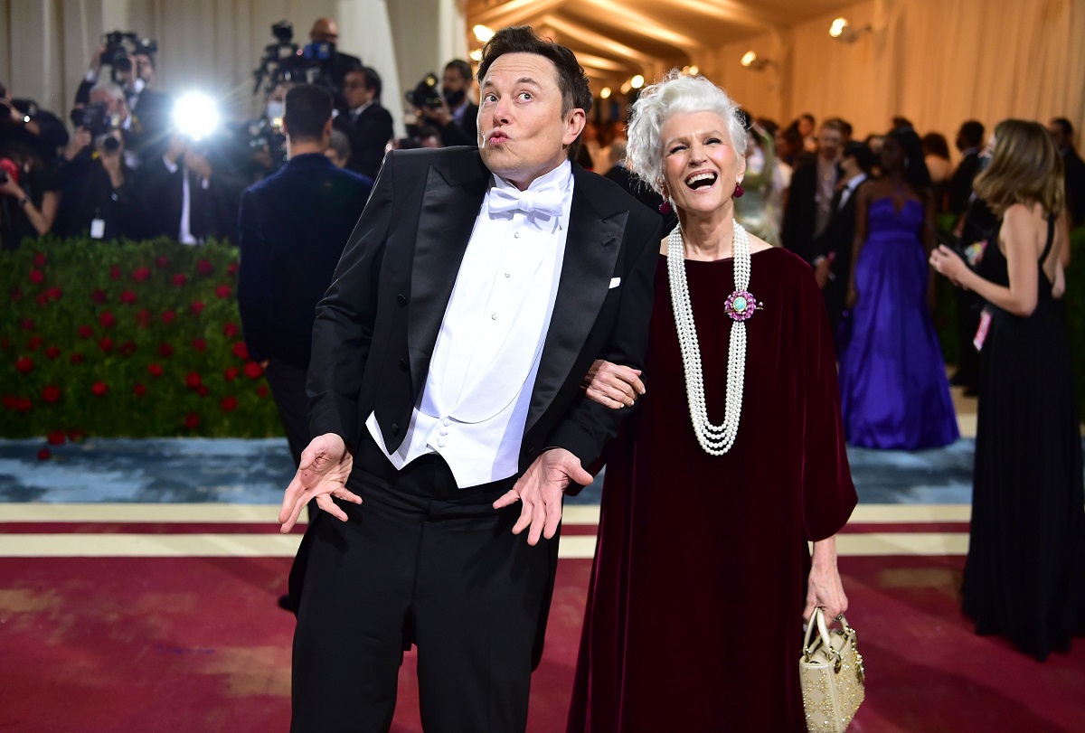 Elon Musk și Maye Musk pe covorul roșu MET Gala 2022. El poartă un costum negru, cămașă albă, și ea poartă o rochie roșie