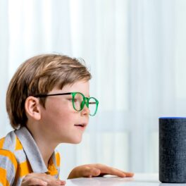 Un copil cu ochelari care vorbește cu Alexa, care va putea imita vocile rudelor decedate