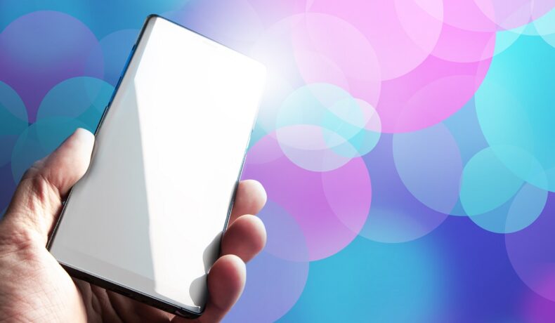 Telefon alb pe fundal cu albastru si mov si roz, in mana unui utilizator, similar cu Nothing Phone 1