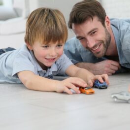 Un tată și băiatul lui, care se joacă cu mașini pe podea. Experții au dezvăluit care e vârsta ideală pentru a deveni tată