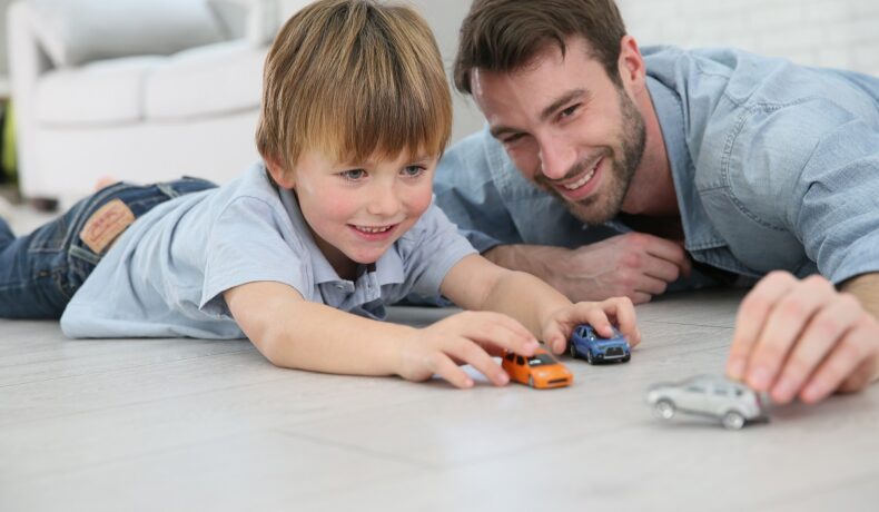 Un tată și băiatul lui, care se joacă cu mașini pe podea. Experții au dezvăluit care e vârsta ideală pentru a deveni tată