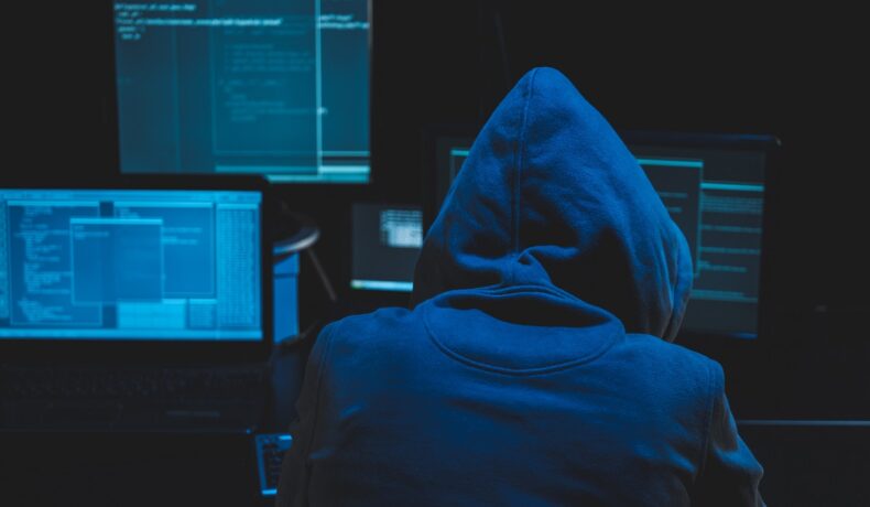 Un hacker care stă cu spatele, în fața unor monitoare, similar cu cel care ar fi obținut datele personale ale unui miliard de cetățeni chinezi