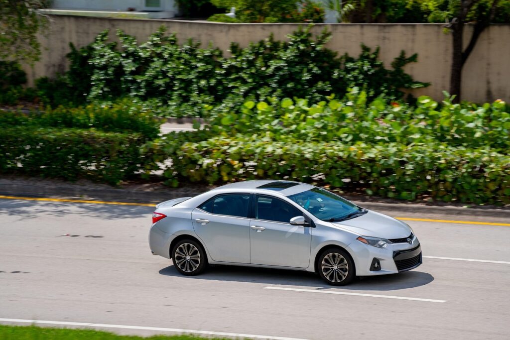 Toyota Corolla albă, în mers, pe șosea