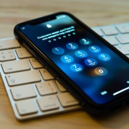 telefon Apple pe o tastatură albă, pe un birou de lemn. apple ar putea elimina parolele în curând