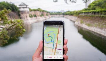 Utilizator care ține un telefon cu Google Maps în mână, în fața unui râu. O familie s-a pierdut în sălbăticie 48 de ore din cauza Google Maps