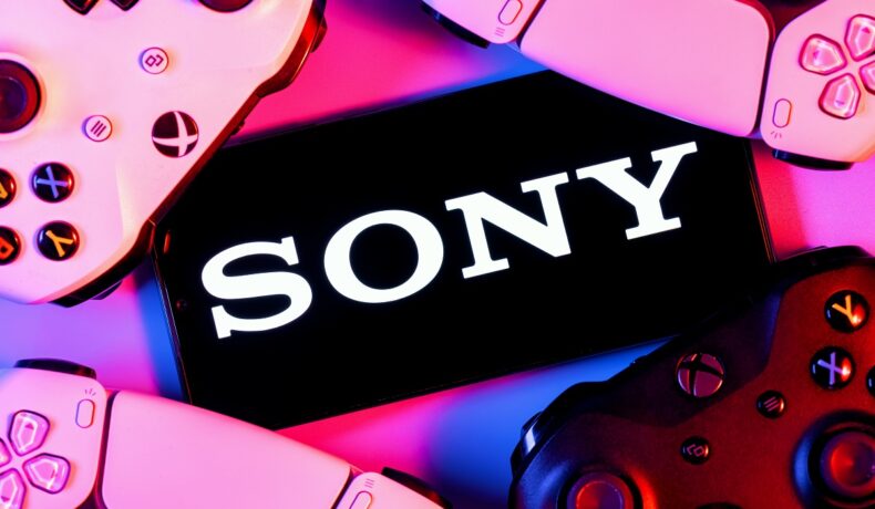 Sony scris pe ecranul unui telefon, alb pe negru, înconjurat de lumină mov, cu mai multe console. Recent, Sony a fost dat în judecată