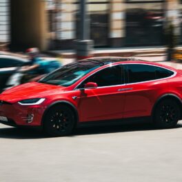 Mașină Tesla roșie pe drum. Unii proprietari Tesla își îun copiii în fața mașinilor