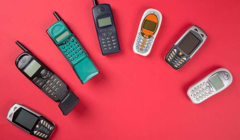 O masă roșie pe care se află telefoane vechi pentru a arăta cum s-au schimbat telefoanele mobile în ultimii ani