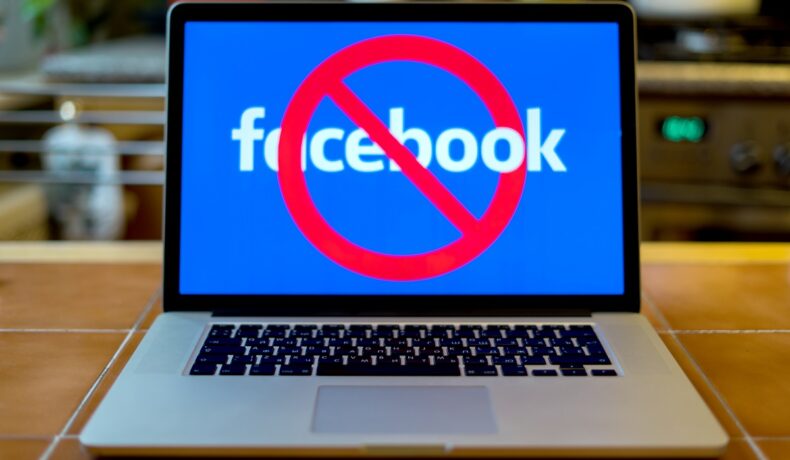 Laptop care are Facebook pe ecran, cu albastru și un simbol roșu de interzis. Experții au dezvăluit ce își apare când cineva te blochează pe Facebook