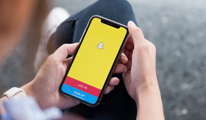 O femeie care ține în mână un tlefon deschis în aplicația de Snapchat
