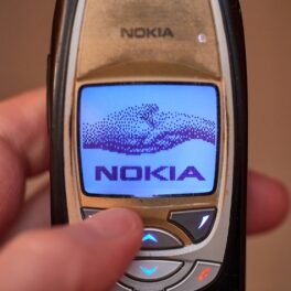 Telefon vechi Nokia ținut în mână de utilizator, cu simbolul pe ecran. Nokia a dat recent în judecată Oppo