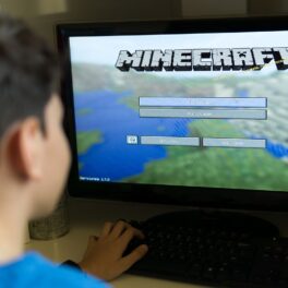 Adolescent care stă în fața unui calculator, cu Minecraft pe ecran, jocul în care tot universul cunoscut a fost recreat