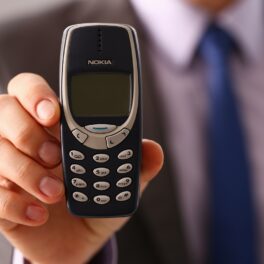 Un bărbat care ține în mână un telefon vechi Nokia 3310