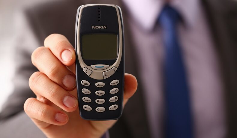 Un bărbat care ține în mână un telefon vechi Nokia 3310