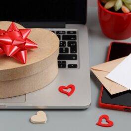 Cadou în formă de inimă, cu fundă roșie, pe un laptop, care se numără printre acele cadouri tech cu prețuri accesibile